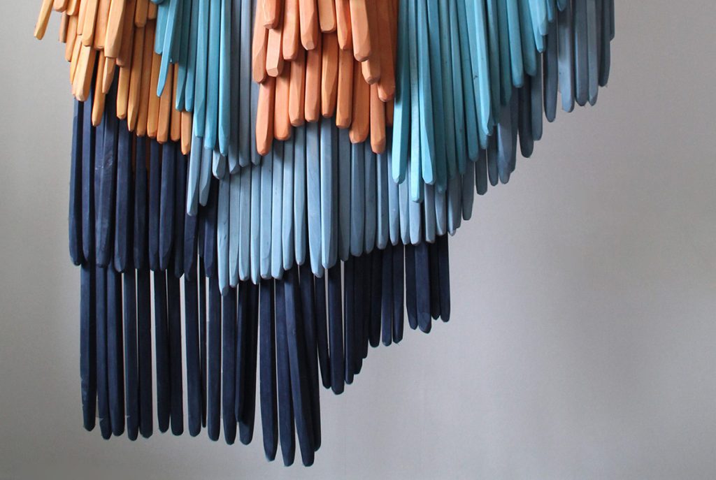 Hängarnde träskulptur i olika nyanser av blått och orange, av Laura Blake